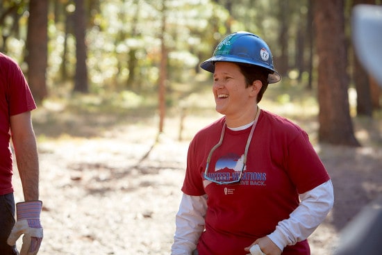 American Hiking Society volunteer with hard hat and gloves laughs.