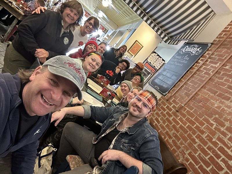 The volunteer group of 13 takes a group selfie sitting in a restaurant.